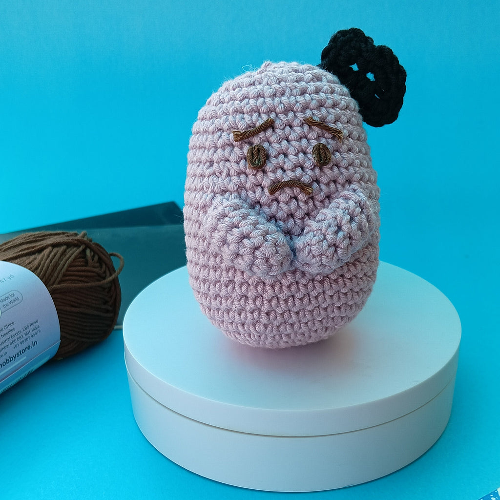 Crocheted character on a white stand with blue background