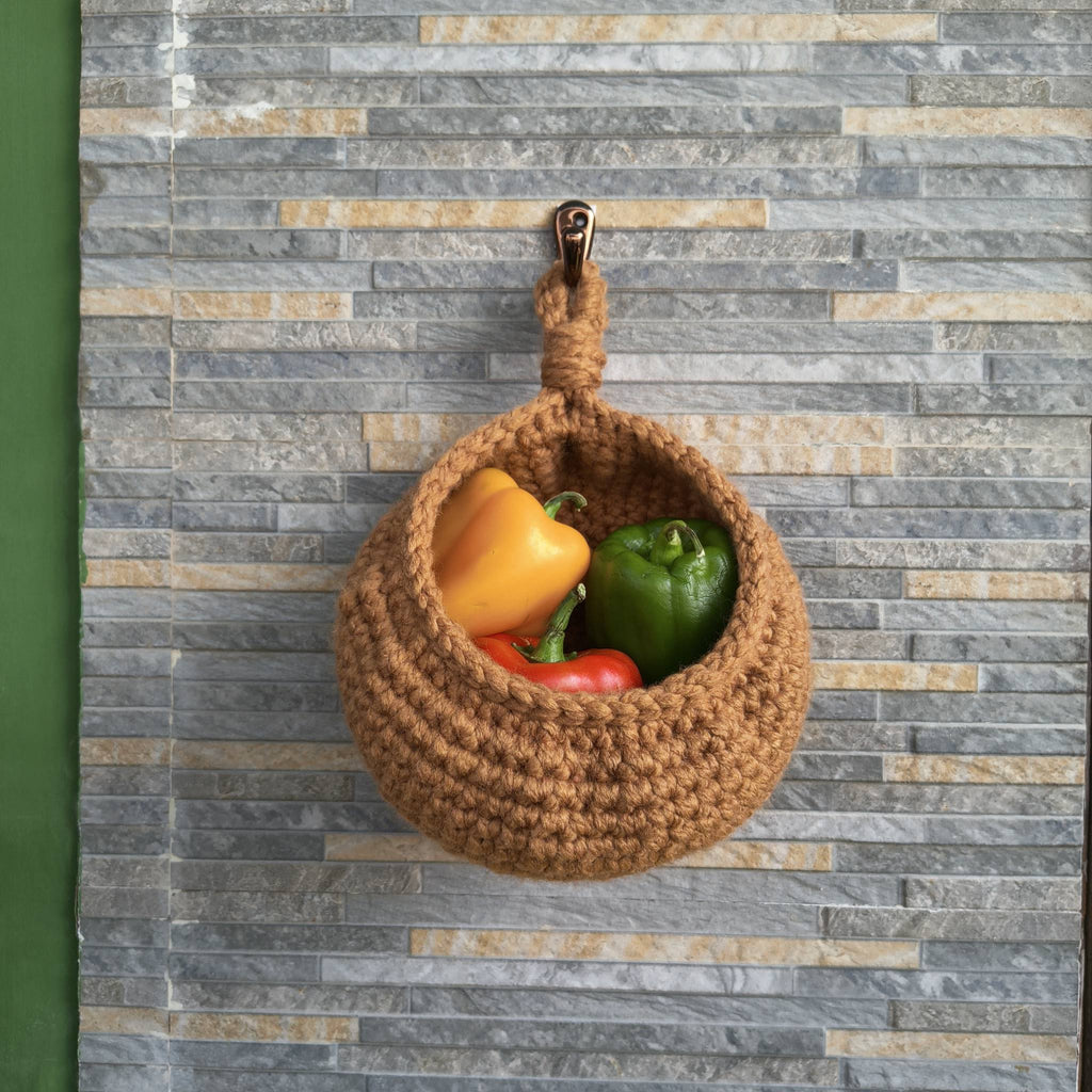 Brown woven basket with colorful peppers on a gray and beige striped background